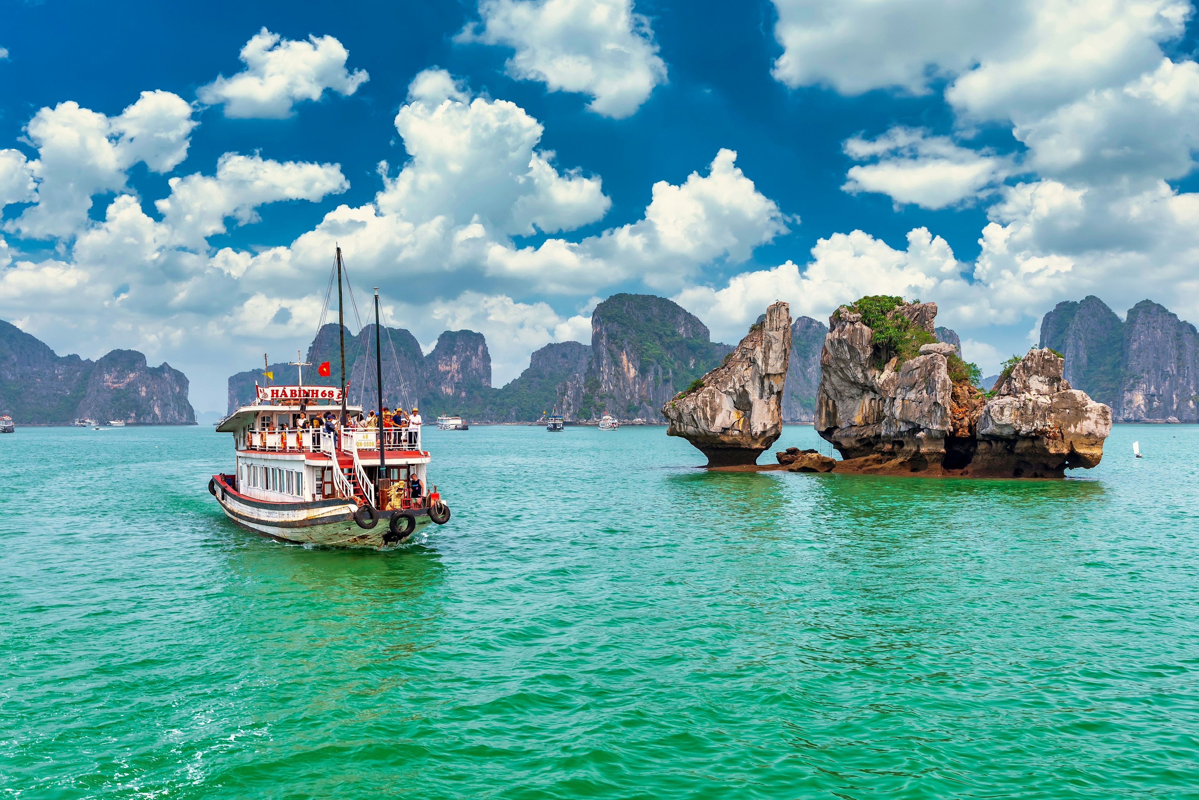 A boat floats between islands in Halong Bay, Vietnam