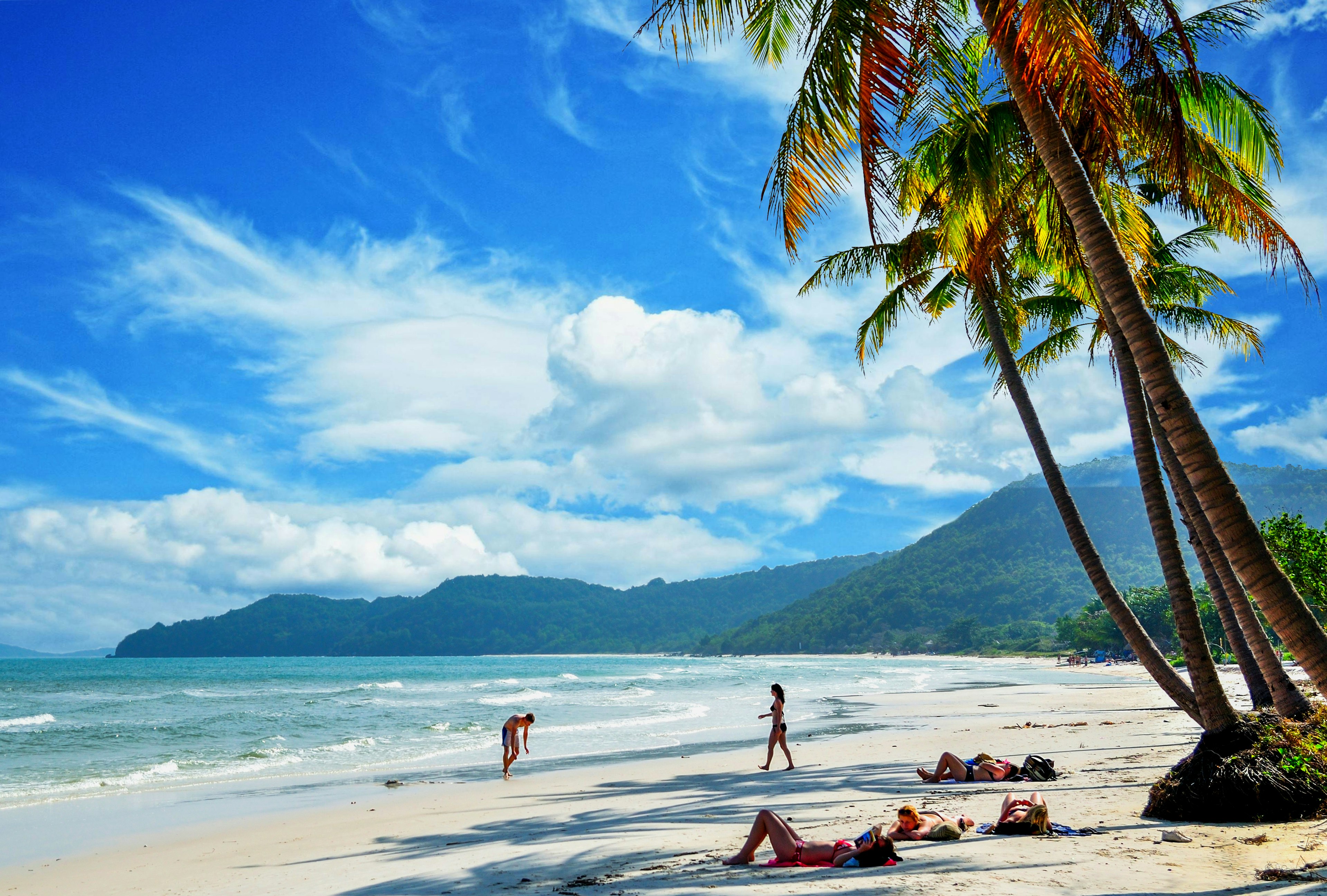 People on white sand beach under palm trees at Khem Beach, Phu Quoc Island, Vietnam