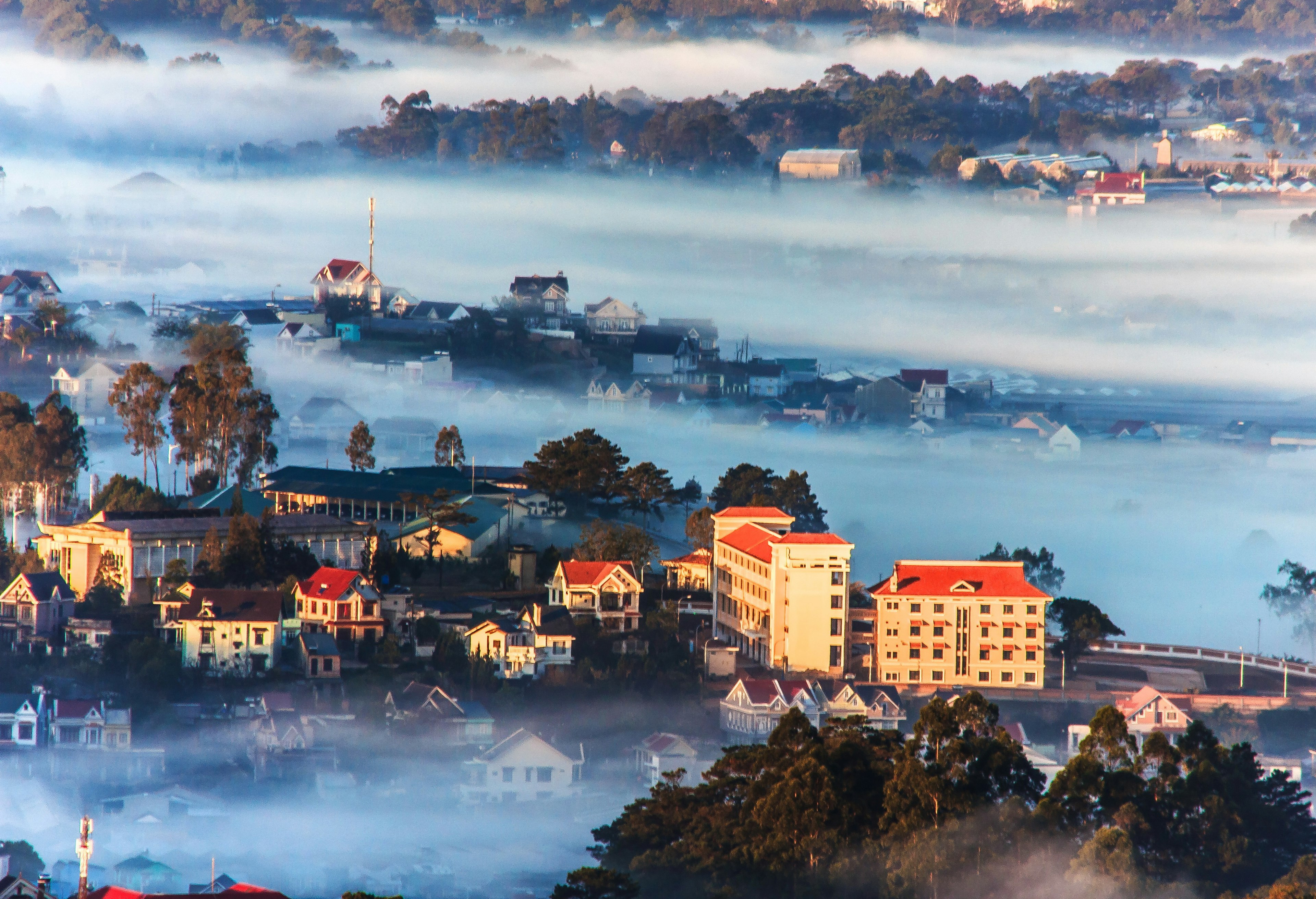 An aerial view of the Dalat mountain station in Vietnam. The city is shrouded in fog due to its high altitude, so only a few buildings are visible.