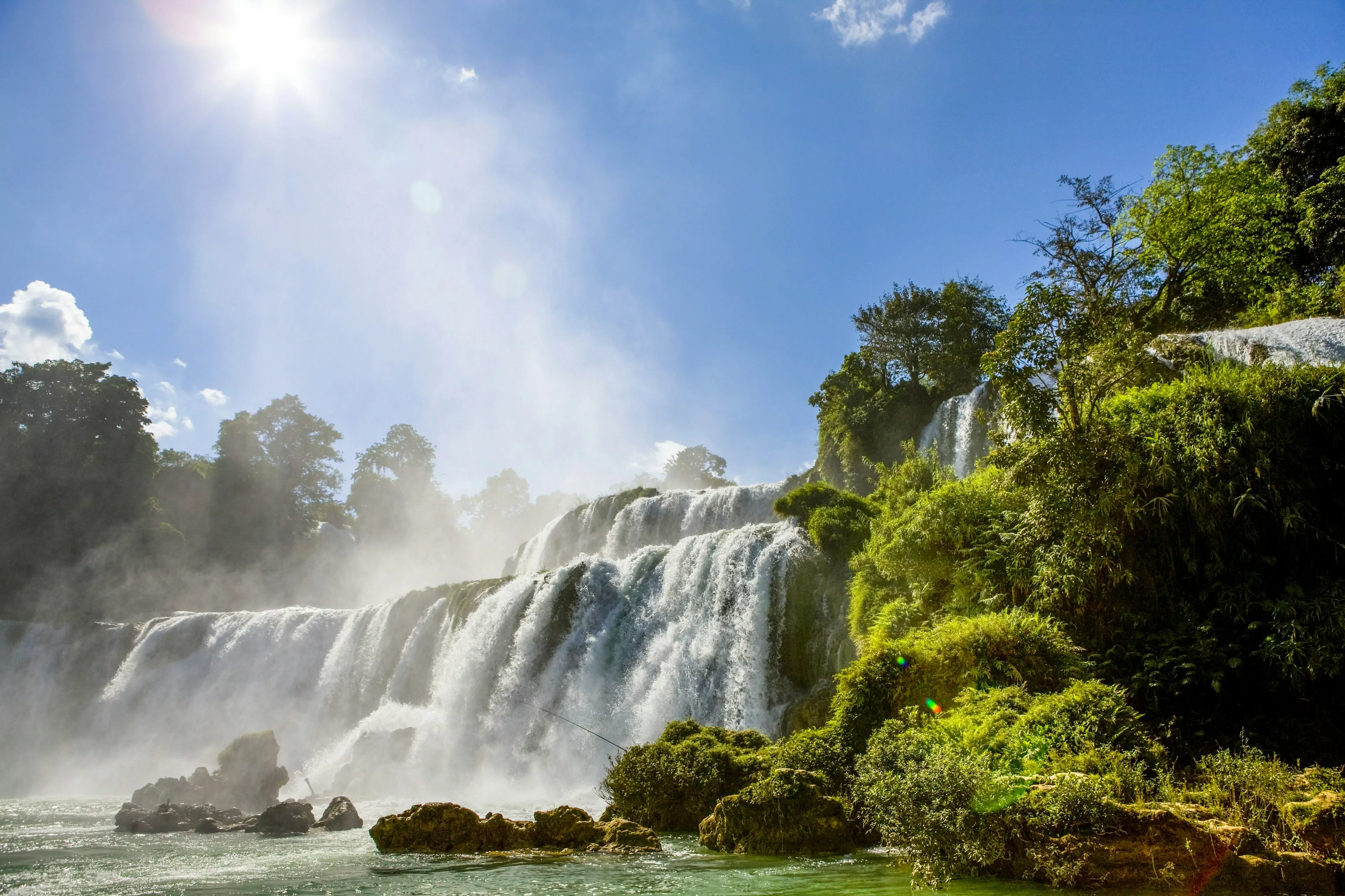 A huge waterfall located on the border of Vietnam and China. Large amounts of water flow over the falls.