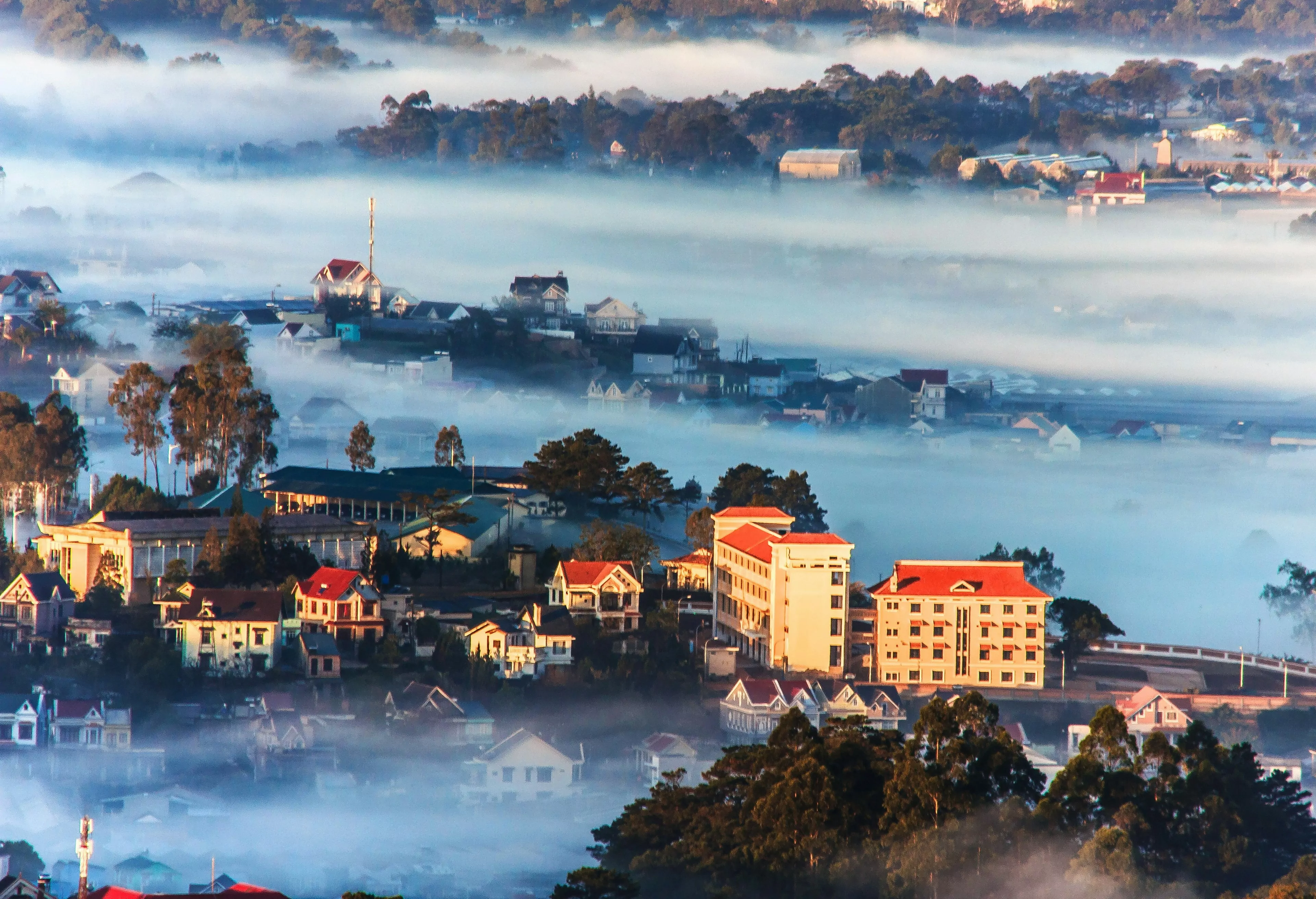 An aerial view of the Dalat mountain station in Vietnam. The city is shrouded in fog due to its high altitude, so only a few buildings are visible.